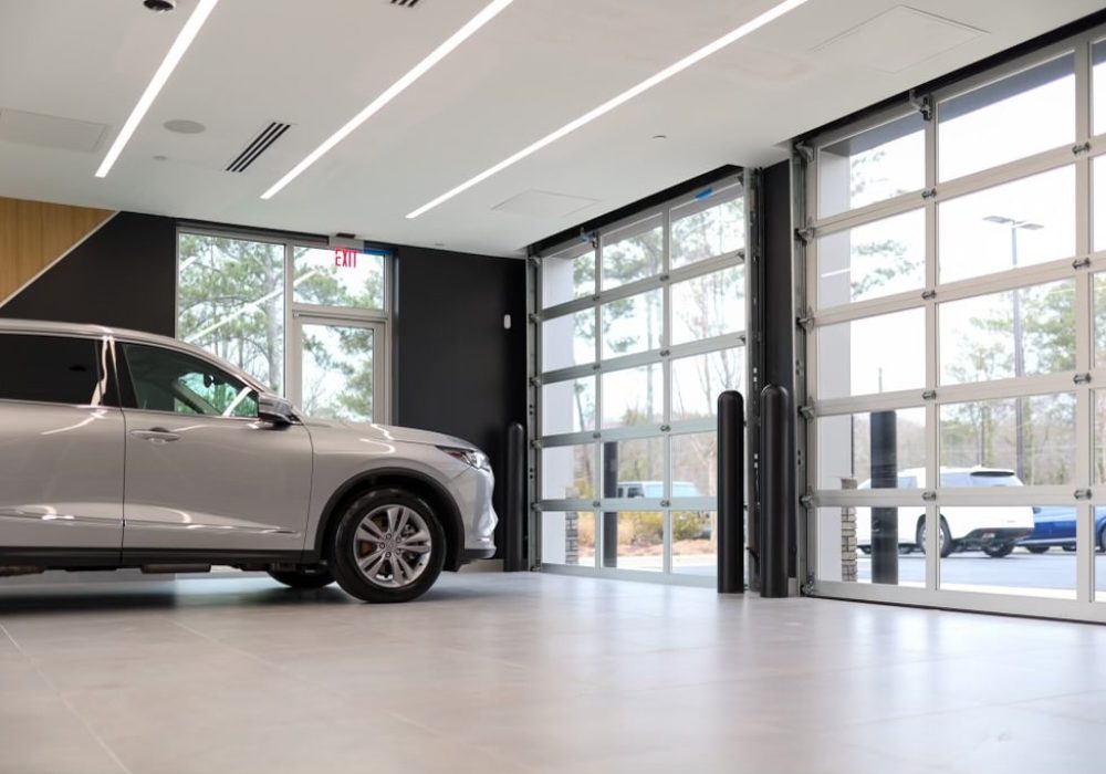 A showroom featuring large glass doors allowing natural light to flood the space, highlighting the vehicles inside.