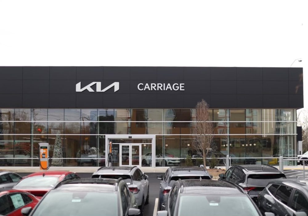 Front view of the Kia dealership main entrance with the brand logo and showroom windows.