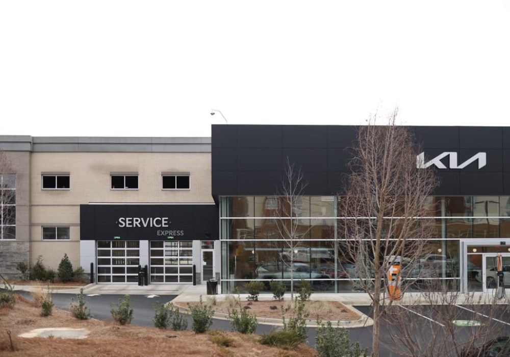 Exterior view of the Kia dealership alongside its service center, featuring a modern design.