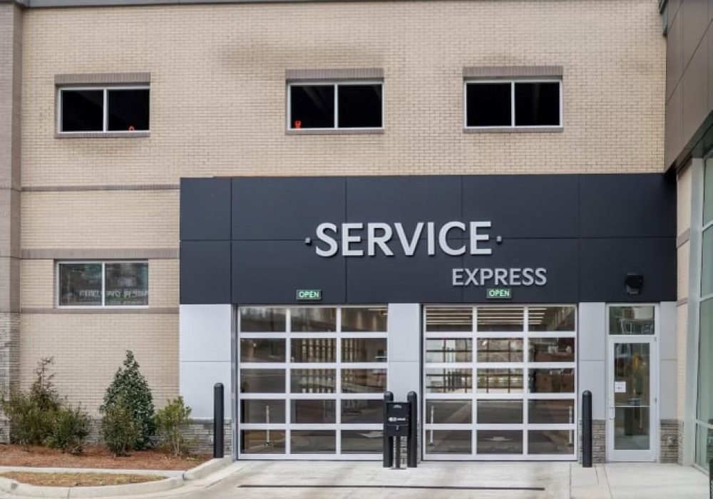 Kia dealership’s service department entrance with signage and customer parking.