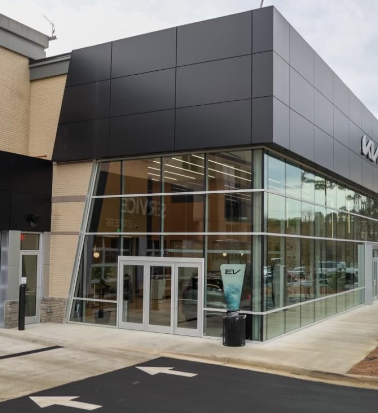 Exterior view of a Kia dealership with EV charging stations in the parking lot.