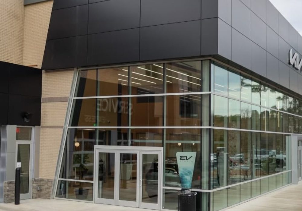 Exterior view of a Kia dealership with EV charging stations in the parking lot.