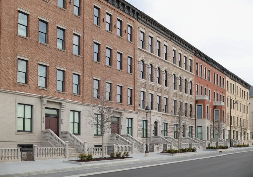 A row of elegant brick townhouses with traditional architectural details and staircases leading to the entrances.