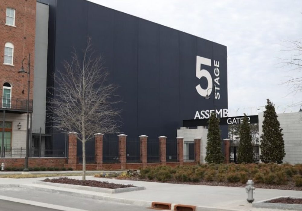 A sleek, black-walled film production studio labeled "Stage 5" with a gated entrance and landscaped surroundings.