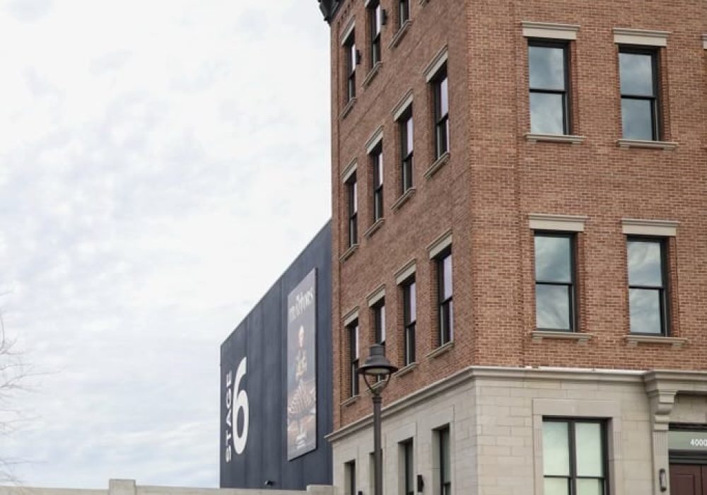 A historic-style brick building adjacent to a large black "Stage 6" film studio, blending classic and modern elements.