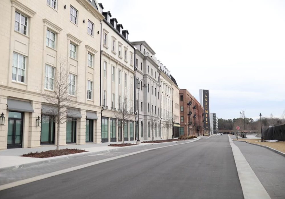 A row of cream-colored townhouses with large windows, ideal for residential or mixed-use purposes.