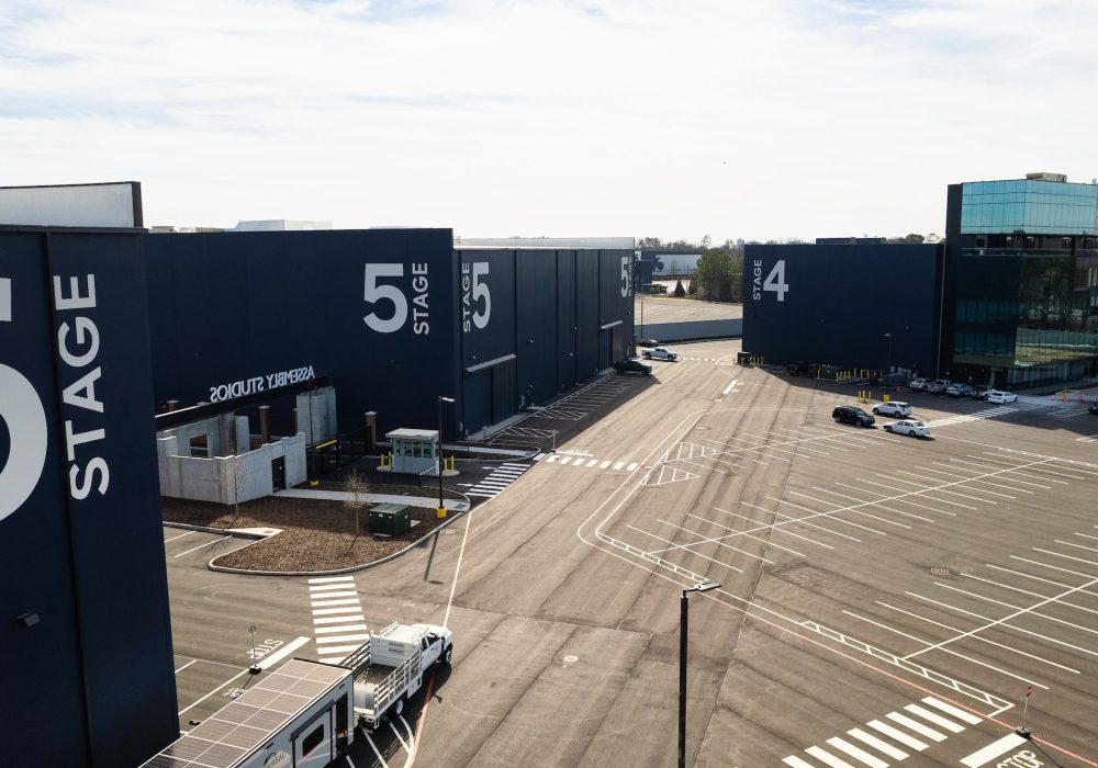 Aerial view of Assembly Studios showing Stages 4, 5, and 6 with modern black exteriors and a large parking area.