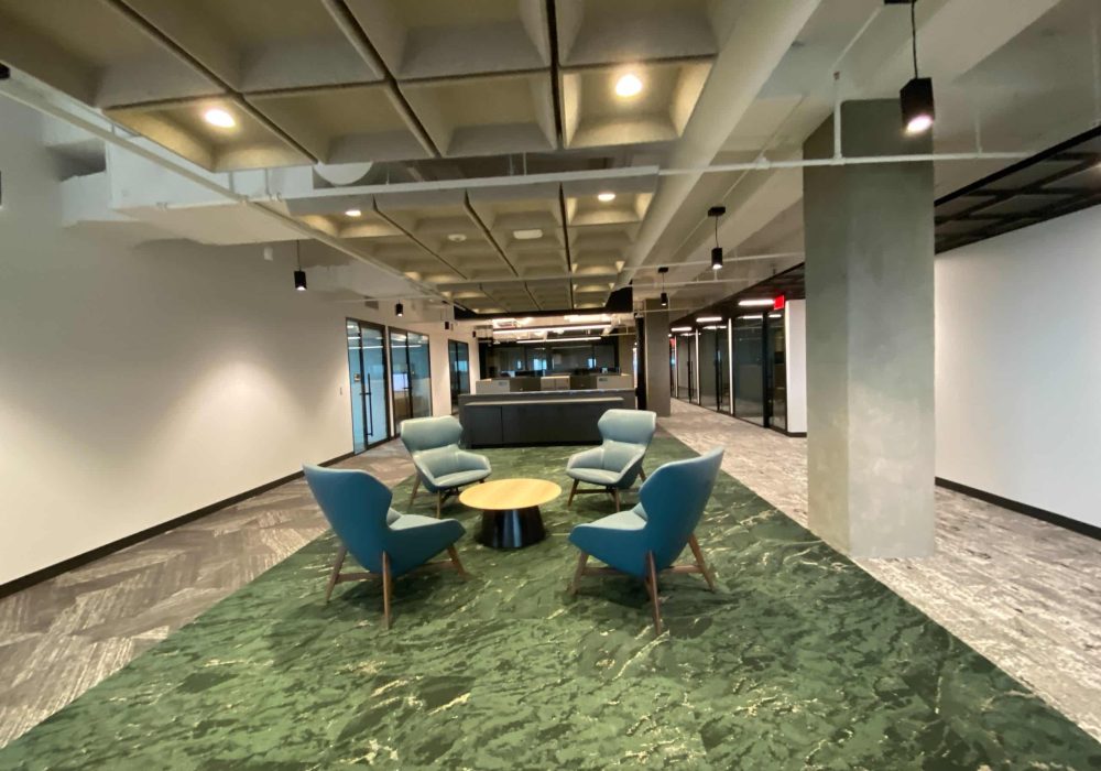 A comfortable office lounge area with accent chairs, a round table, and modern lighting.