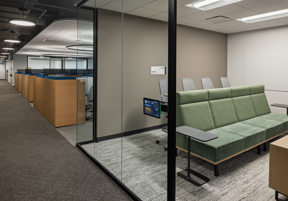 A modern open office space at OneDigital with individual workstations, glass-walled meeting rooms, and a contemporary color scheme.